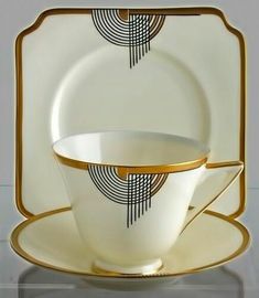 a white and gold dinner set with two cups, saucers and plates on it