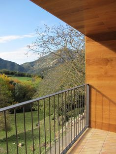 a balcony with mountains in the background and trees on the other side that overlooks a valley