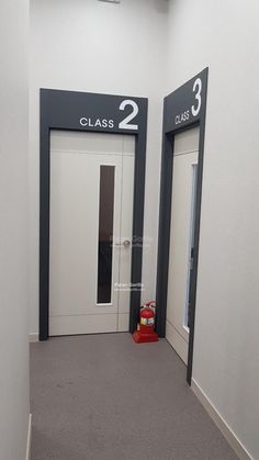 an empty hallway with two doors and a red fire hydrant in the corner next to it