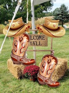 two cowboy boots sitting on top of hay in front of a welcome yall sign