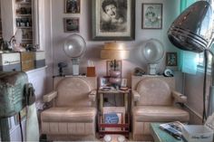 a living room filled with furniture and lots of framed pictures on the wall next to a lamp