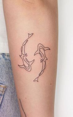 a woman's arm with two dolphins tattoo on the left side of her arm