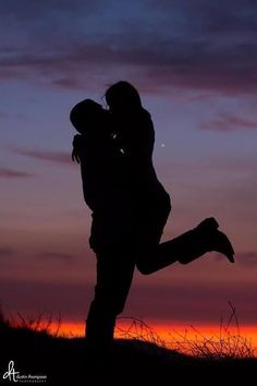 a man and woman kissing in front of a purple sky with the sun setting behind them