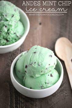 two bowls filled with green ice cream on top of a wooden table next to a spoon