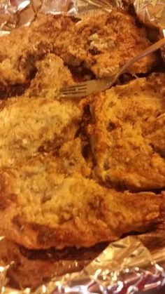 some fried food is sitting on foil and ready to be eaten with a knife and fork