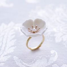 The beautiful plum blossom, who never fears frost and snow, bravely flowers in the coldest seasons, awakening spring and bringing hope. The pure and delicate petals deserve your extra love and care. Ring is made of porcelain flower; gold-plated silver ring and a small freshwater pearl. Material: Handmade porcelain plum blossom; Gold-plated silver ring; Small freshwater pearl. Gold- or silver-plated colour will fade over time. This is a normal result from long-term wear and contact with air. Howe Delicate White Flower Ring, Delicate White Flower-shaped Ring, Delicate White Flower Shaped Ring, Delicate White Flower Ring For Wedding, White Flower Ring For Promise, White Flower Shaped Anniversary Ring, White Birth Flower Ring For Wedding, White Birth Flower Wedding Ring, Nature-inspired White Flower Ring