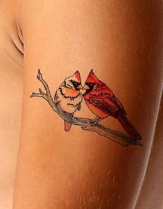 a woman's thigh with a bird tattoo on the side of her leg and a red cardinal sitting on top of it