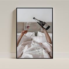 a woman laying in bed holding a glass of wine