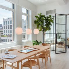 a dining room table and chairs in front of large windows