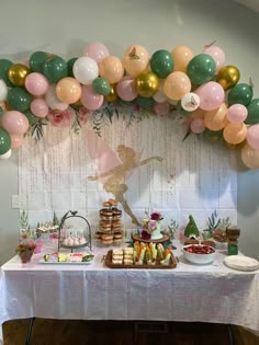 a table topped with lots of desserts and balloons above the top of it is a ballon arch