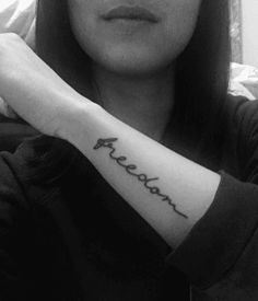 a woman with a small tattoo on her arm that says freelan in cursive writing