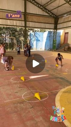 children playing basketball in an indoor court with yellow cones on the ground and people standing around