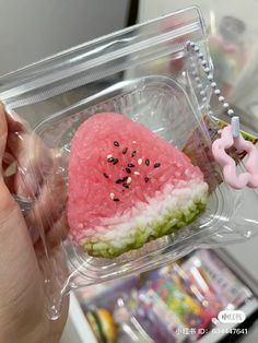 someone is holding a watermelon slice in a plastic container with seeds on it