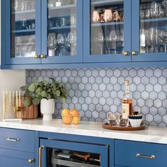 a kitchen with blue cabinets and white counter tops, filled with wine glasses and bottles