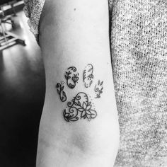 a black and white photo of a dog paw tattoo on the left upper half of the arm