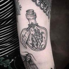 a woman's arm with a tattoo on it and a bottle filled with herbs