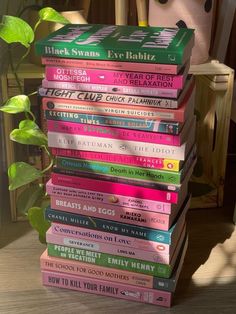 a stack of books sitting on top of a wooden table next to a potted plant