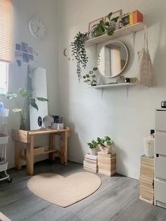 a living room with white walls and wooden flooring, plants on shelves above the desk