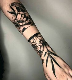 a person's arm with flowers and leaves tattooed on the wrist, in black ink