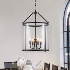 a chandelier hanging from the ceiling over a dining room table with flowers on it