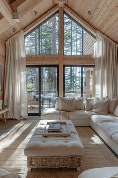 a living room filled with lots of furniture next to a large glass window covered in white curtains