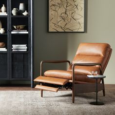 a brown recliner chair sitting in front of a book shelf with vases on it