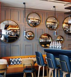 a restaurant with several circular mirrors hanging on the wall and chairs around the bar area