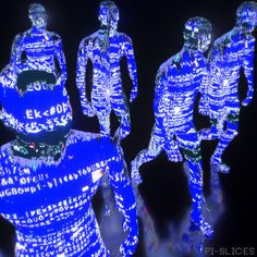 three blue lighted figures in the shape of people with numbers on their faces and arms