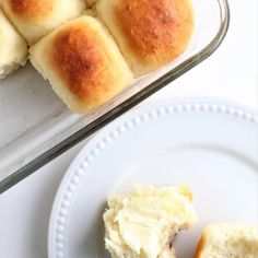 rolls and butter on a plate next to a casserole dish with bread in it