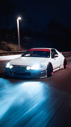 a white car driving down the road at night