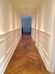 an empty hallway with wood floors and white walls