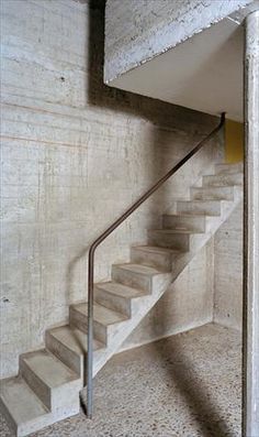 the stairs are made of concrete and have metal handrails that lead up to the second floor