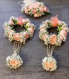 three flower wreaths with pearls and flowers on the ground next to each other in front of a white feather