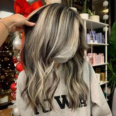 a woman getting her hair cut by someone in front of a christmas tree with ornaments