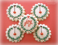 four decorated cookies with the word joy on them are sitting in front of a pink background