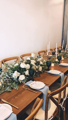 the table is set with white flowers and greenery