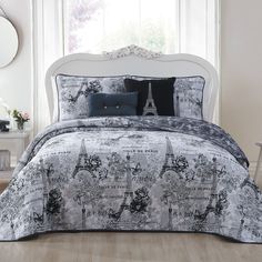 the bed is covered with black and white comforter sets in front of a window