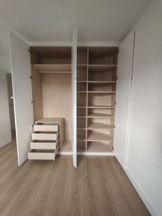 an empty walk in closet with shelves and drawers on the wall, next to a wooden floor