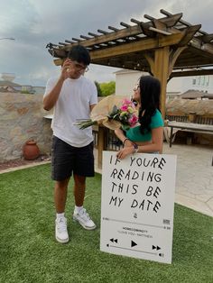 a man and woman standing next to a sign that says if you're reading this be my date