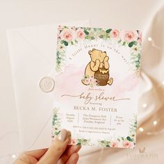 a person holding up a baby shower card with flowers on the bottom and a teddy bear in a basket