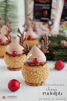 three christmas cupcakes with reindeer antlers on top and candy balls in the background