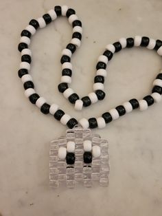 a black and white beaded necklace on a marble counter top next to a plastic container