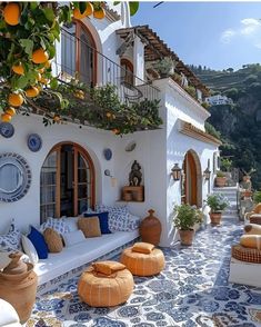 an outdoor living area with oranges and potted plants on the roof, along with white furniture