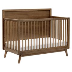 a wooden crib with white sheets on the bottom and side rails, against a white background