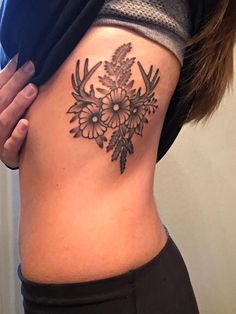 a woman's lower back tattoo with flowers and antlers on her stomach,