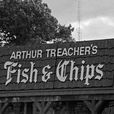 an old sign advertising fish and chips on the side of a building in black and white