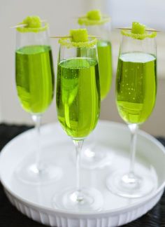 three glasses filled with green liquid on top of a white plate