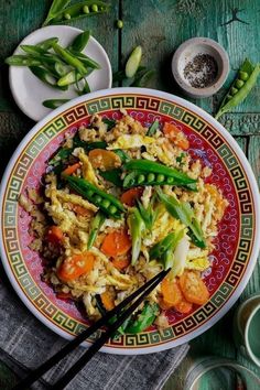 a plate filled with rice and vegetables next to chopsticks