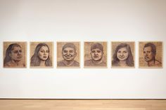 four portraits of people are hanging on the wall in front of a wood floored room