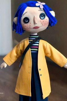 a doll with blue hair wearing a yellow coat